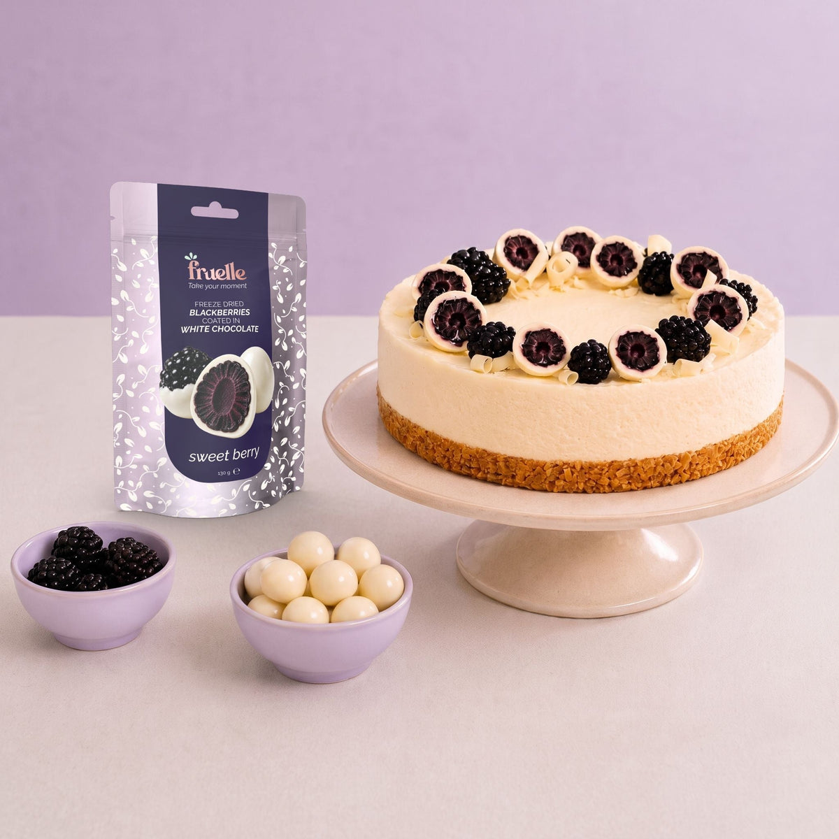 Fruelle Sweet Berry naast een witte chocolade cheesecake versierd met verse bramen, chocoladebramen en witte chocoladeschaafsels